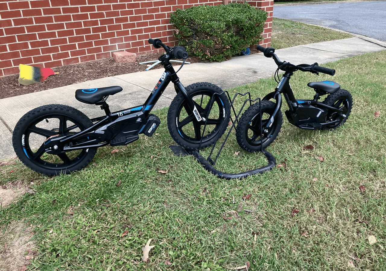 Kids' bikes resting on lawn near sidewalk