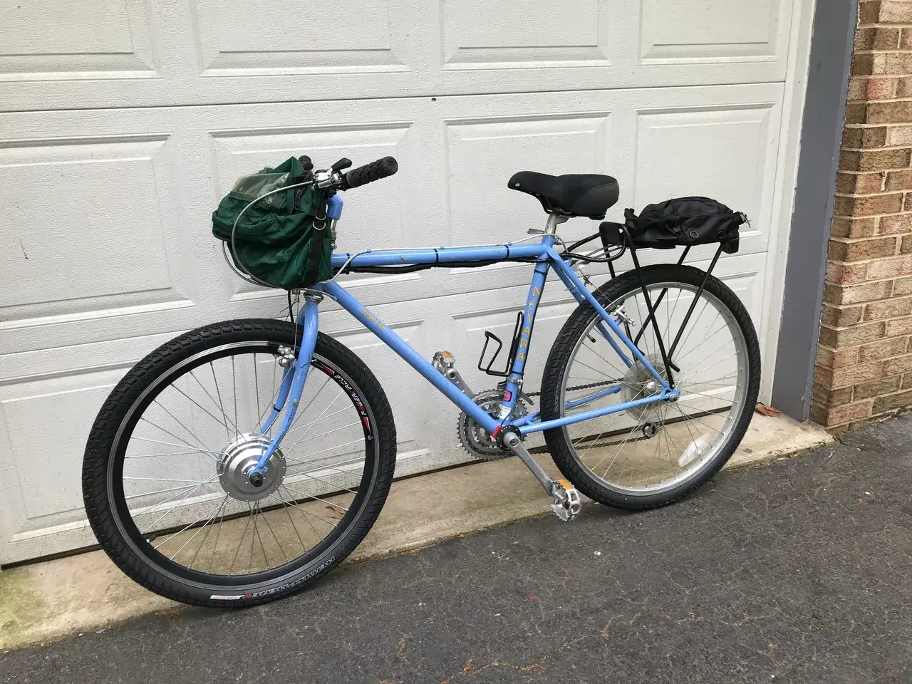 Blue bicycle with bags parked outside garage