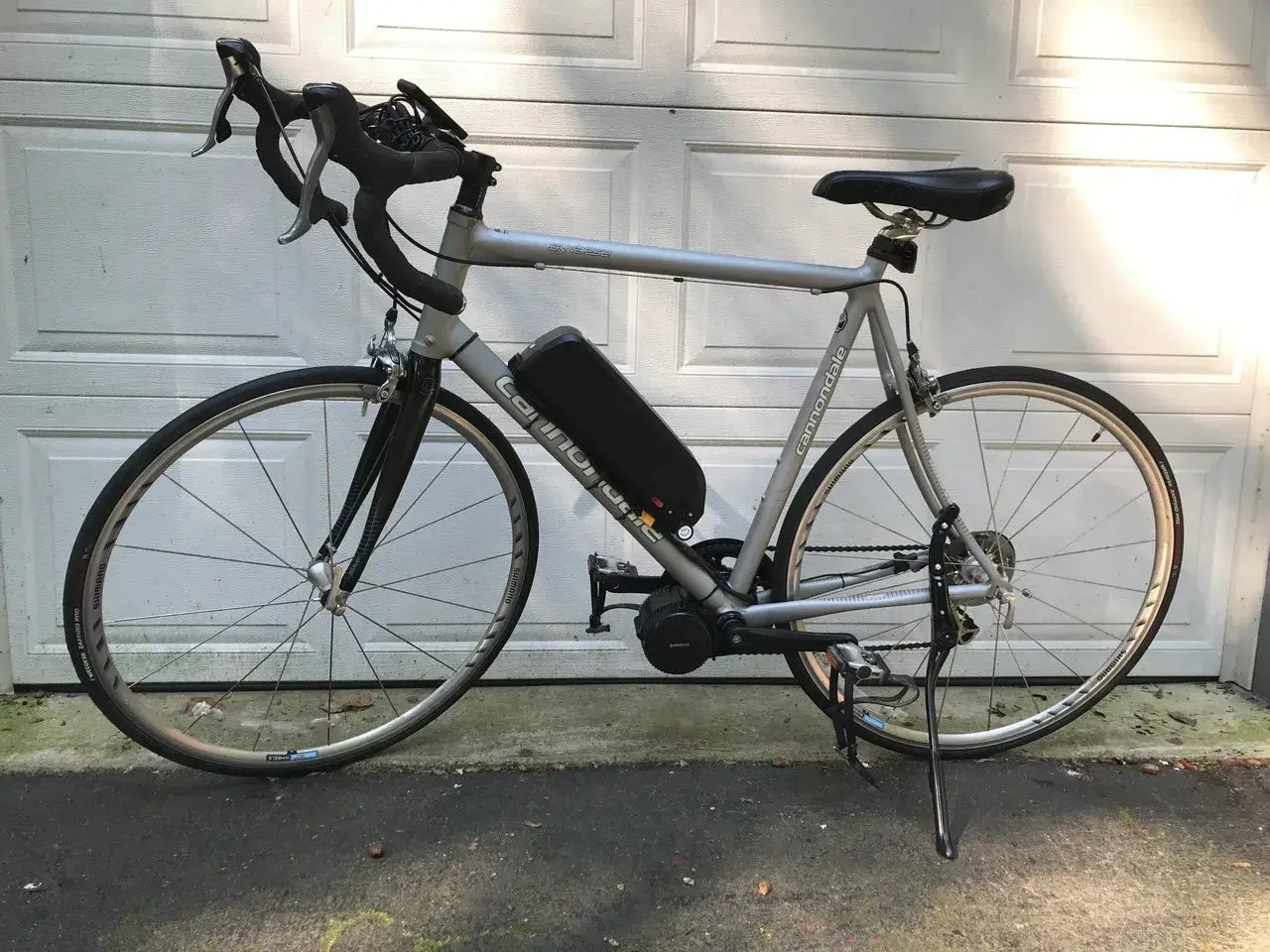 Silver bike with battery on driveway.