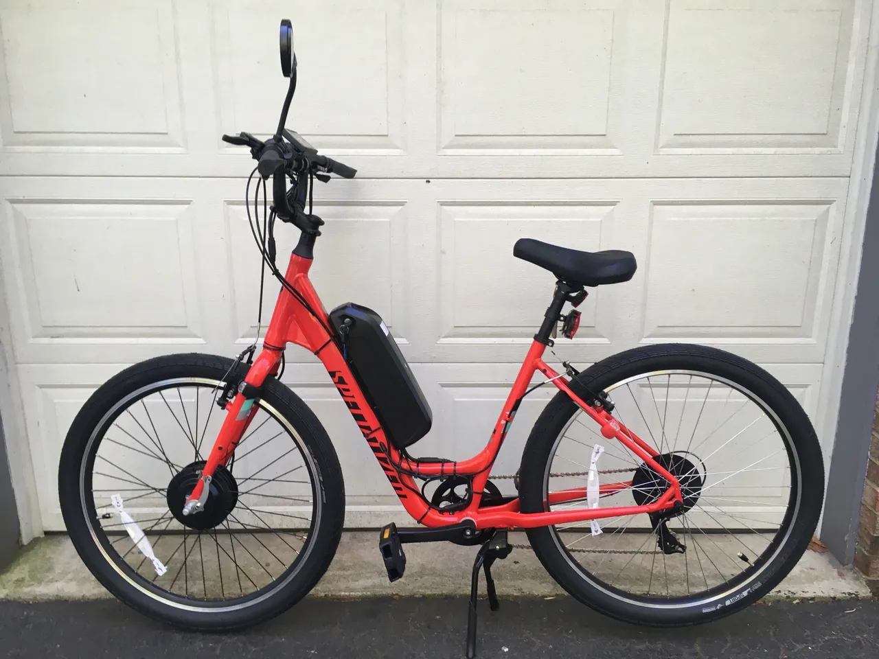 Red electric bike parked near garage door.